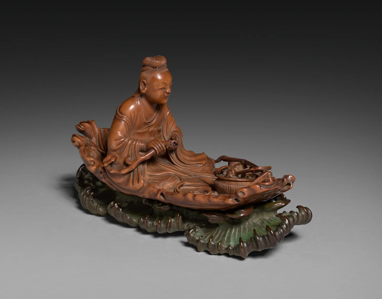 Small Qing dynasty boxwood sculpture of He Xiangu seated on a raft.